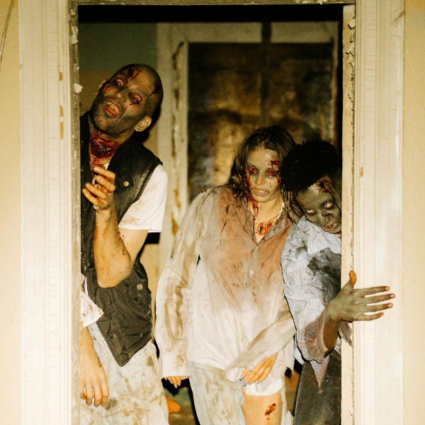 Three zombies peeking through a doorway, with bloodstained clothing and pale, decayed skin.