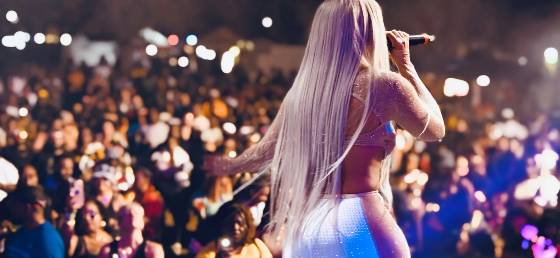 Jadel Performing with long platinum blonde hair on stage in front of a large audience at night. Tampa Bay Carnival 2024