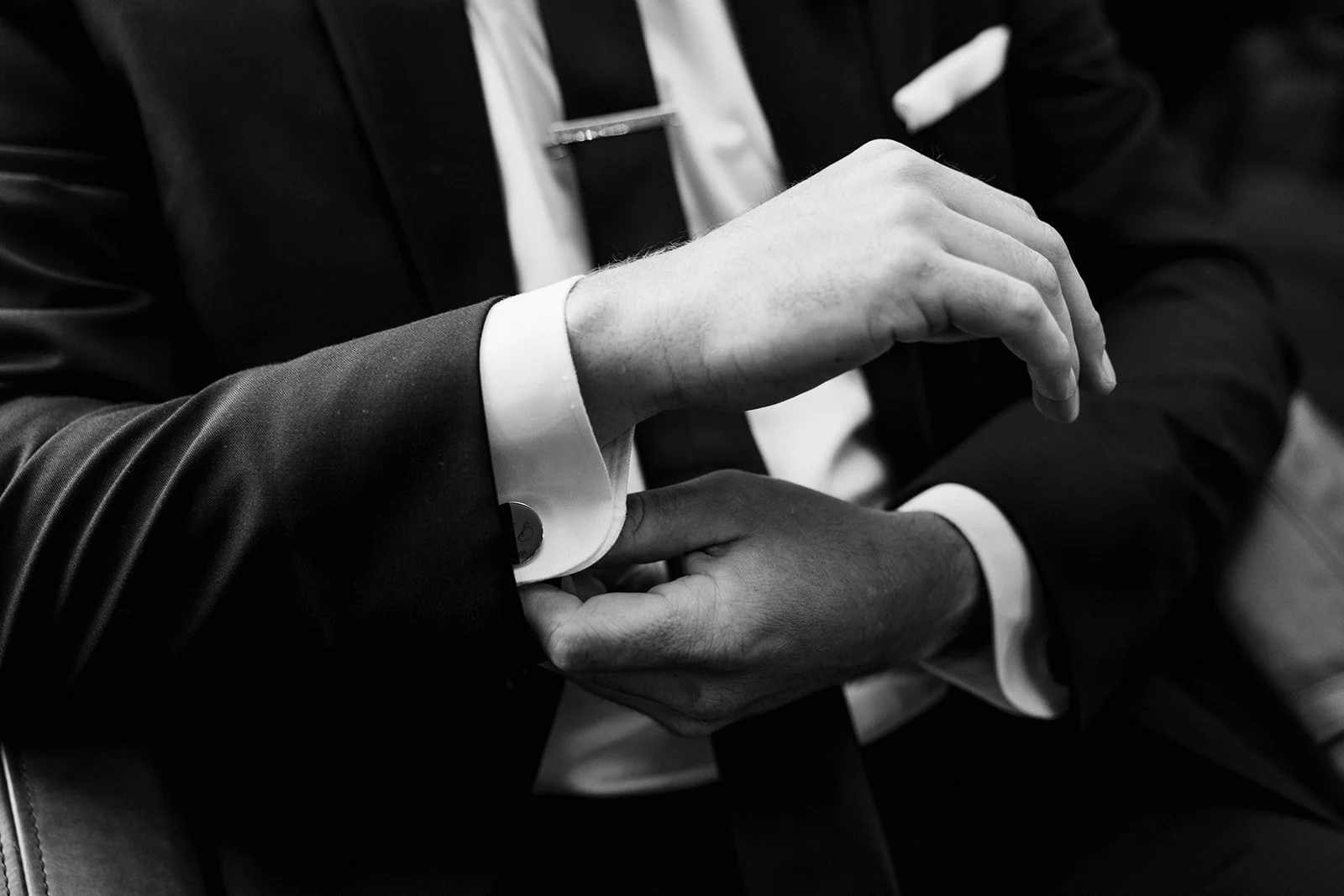 Two people in suits engaging in a hand-holding gesture, with one person's hand gripping the other's wrist in a firm manner.
