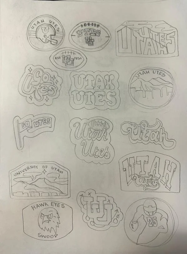 Multiple sketches of logos and emblems related to Utah Utes, including team names, mascots, and symbols, drawn on paper.