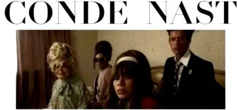 A group of five people standing indoors in front of a wall with a sign that reads 'Conde Nast'.