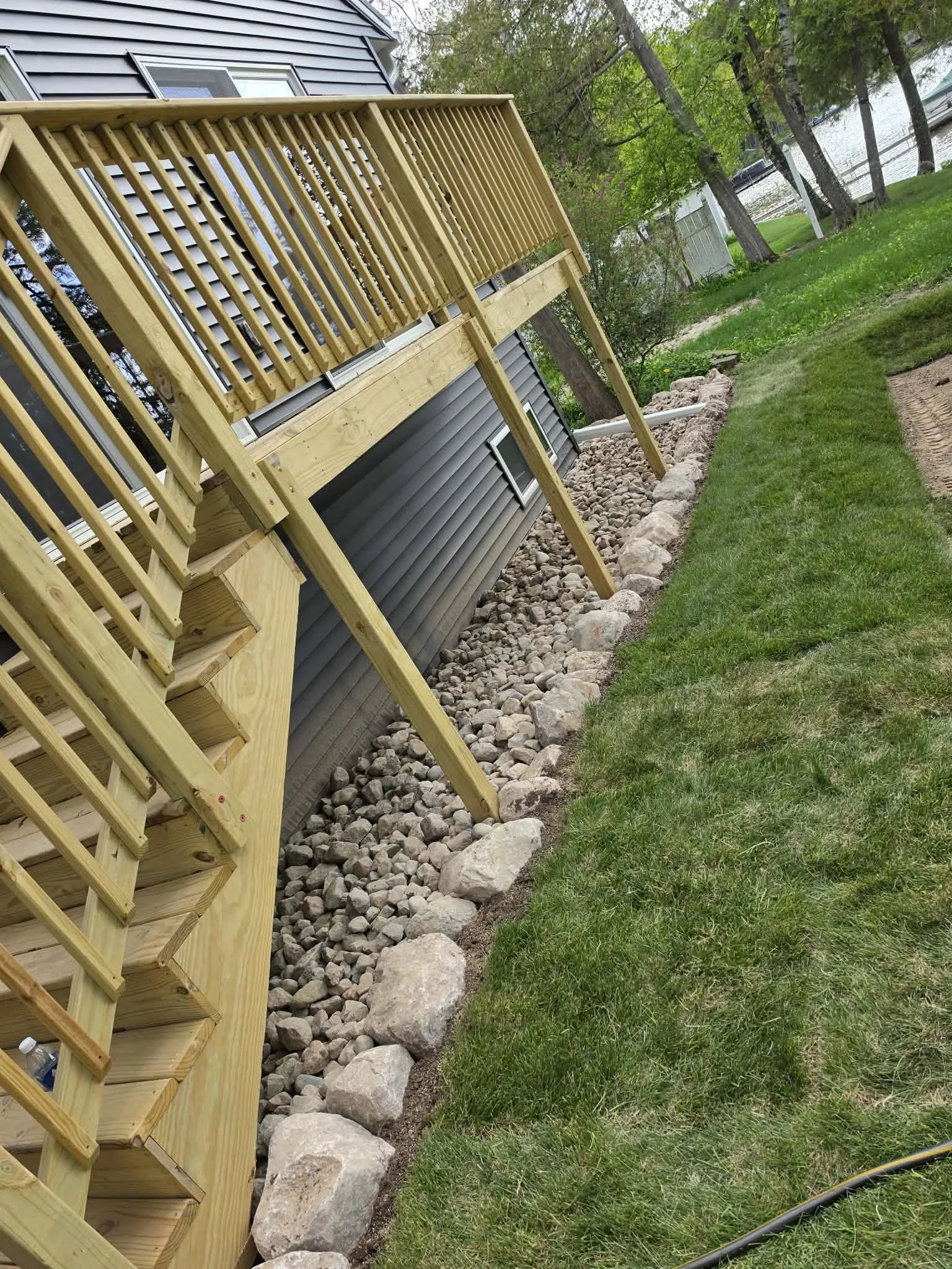 Rock installation — Ground prep and rock border installation alongside deck by Ground & Grid Solutions