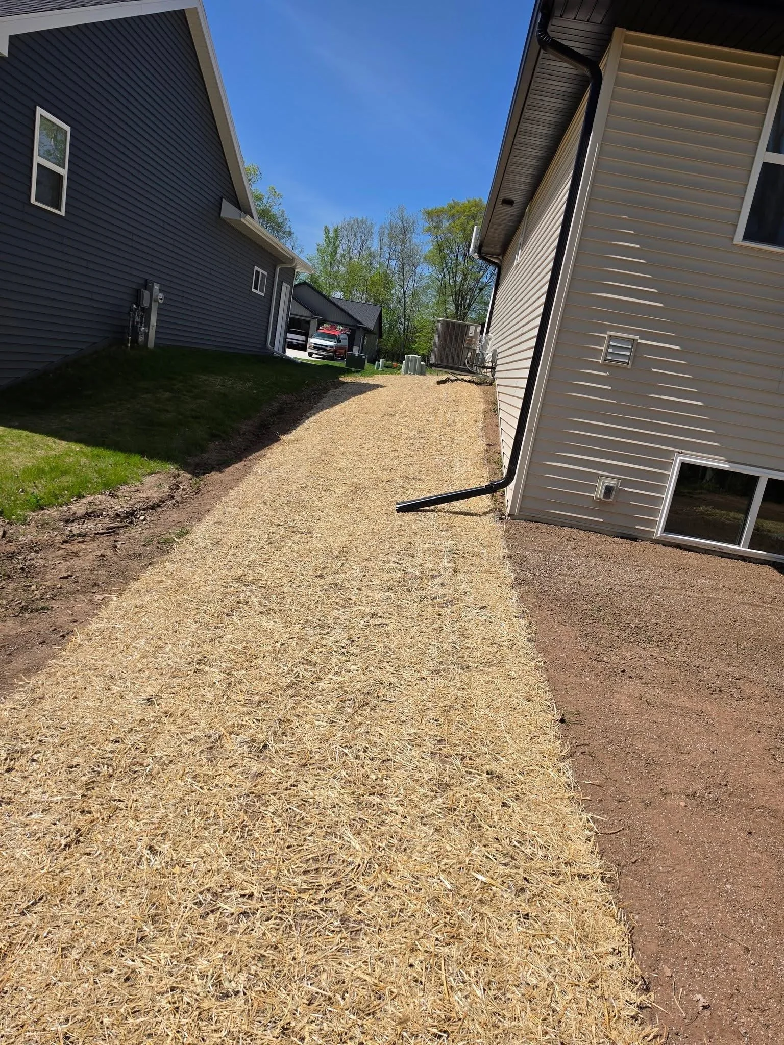 Lawncare prep — Seeded lawn strip with straw erosion blanket between houses by Ground & Grid Solutions