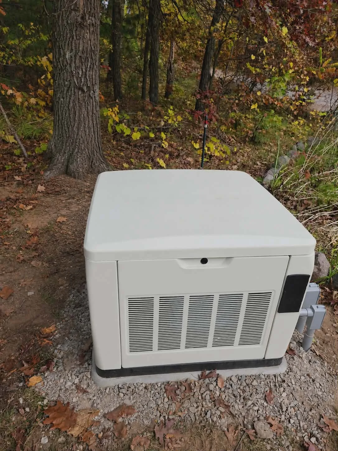 Generator — Standby home generator installed on gravel pad surrounded by Ground & Grid Solutions