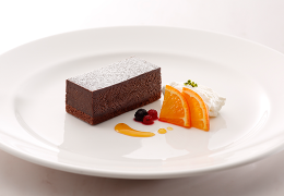 Japan Saveur Chocolate Short Cake with orange slices, berries, and garnish on a white plate.