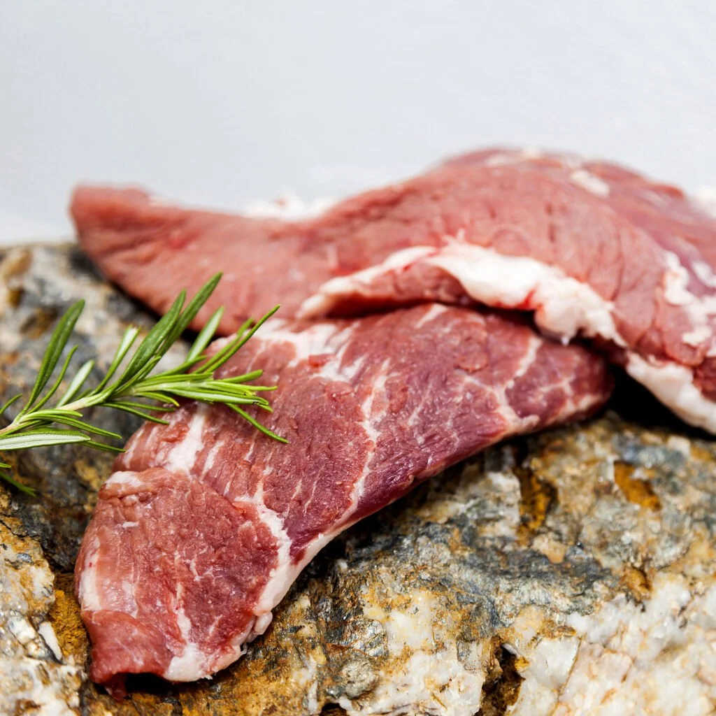 Cesar Nieto Iberico Pork Loin Pluma  garnished with a sprig of rosemary on a rock surface