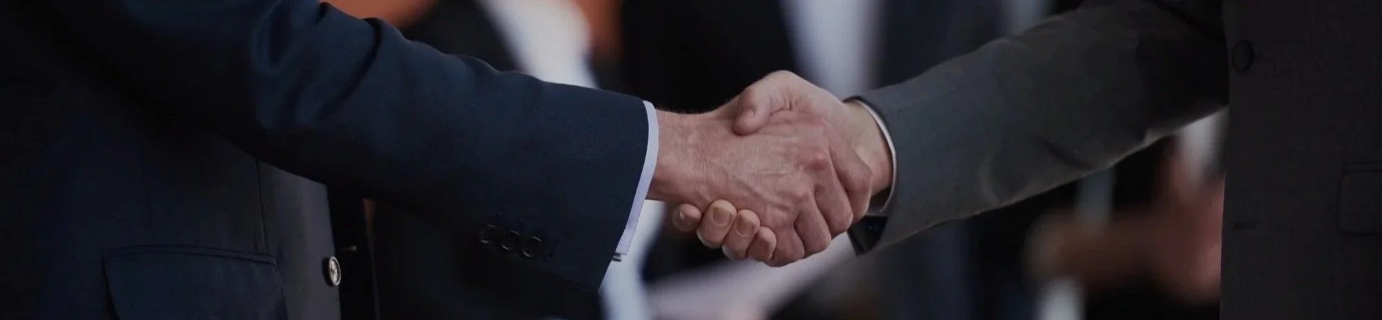 Two people shaking hands, both wearing suits.