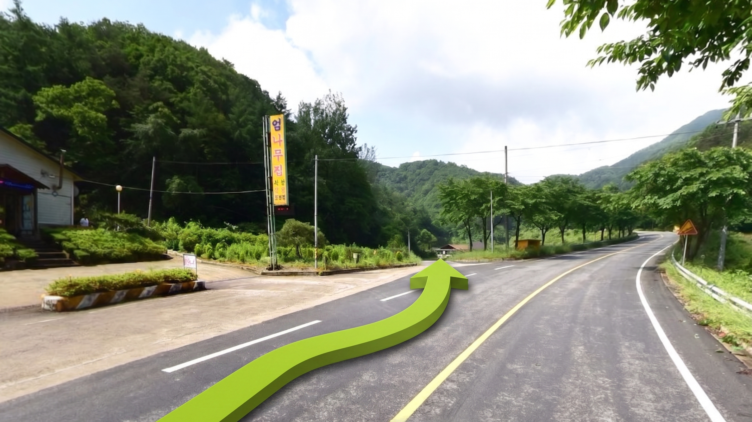 A winding mountain road with a bright green 3D arrow pointing straight ahead and to the right. There are trees and hills in the background, and a street sign written in Korean on the side of the road.