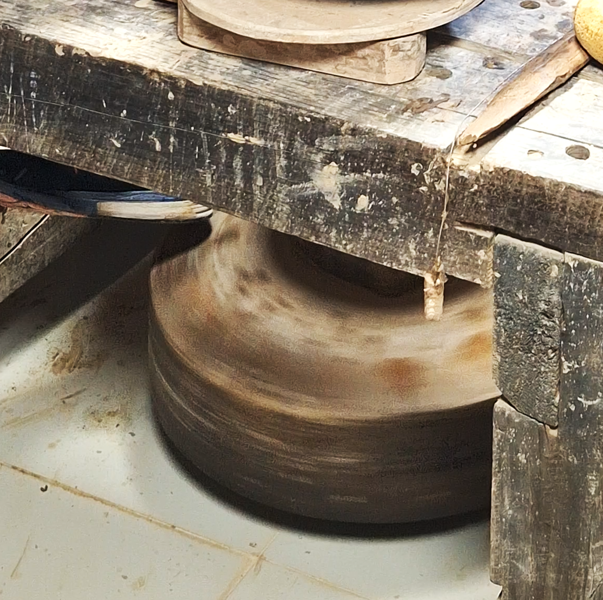 Stacked wooden chopping blocks on a rustic wooden table, with a piece of flint or stone nearby.