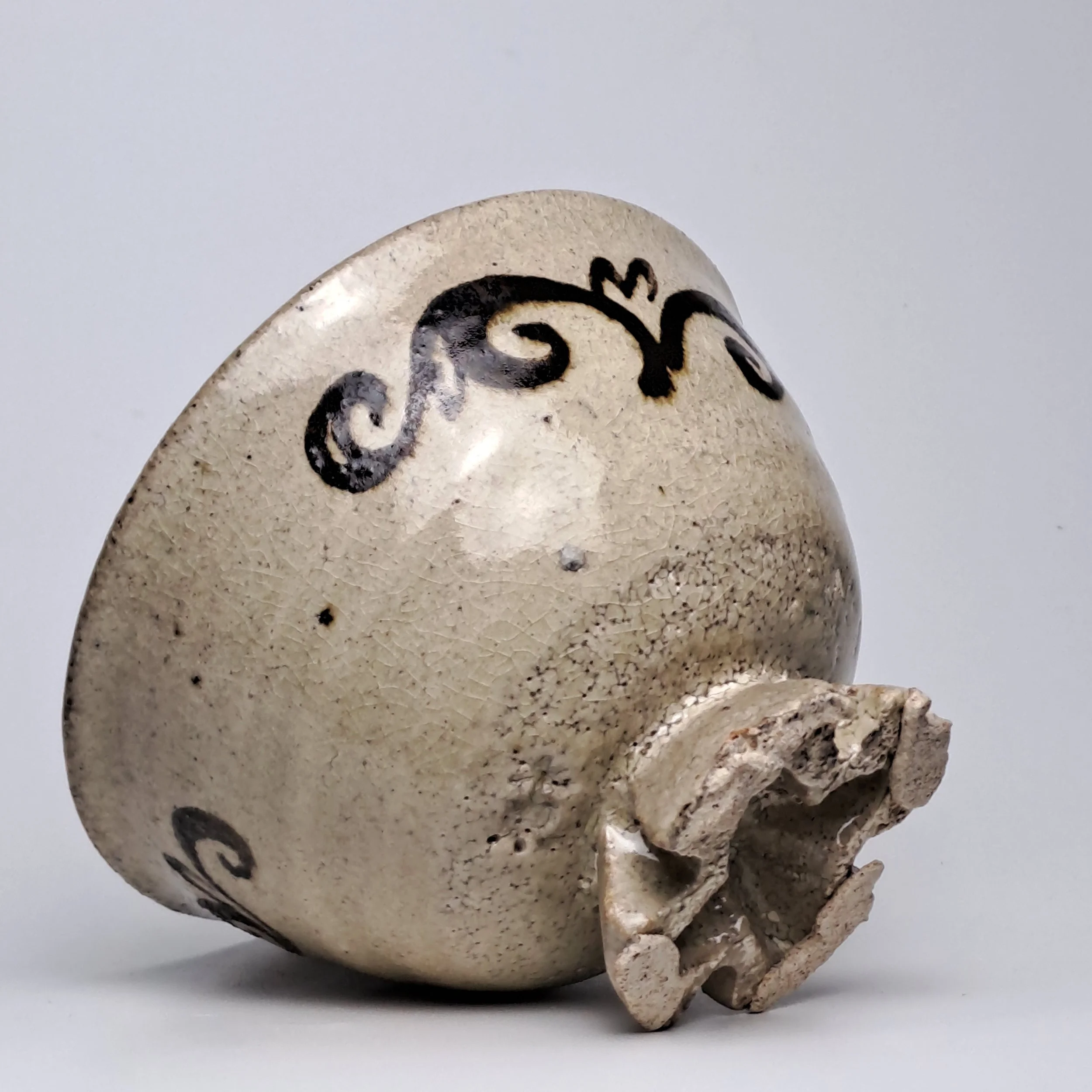 A Buncheong bowl with a cross-shaped foot, adorned with classic iron-painted scroll motifs.
