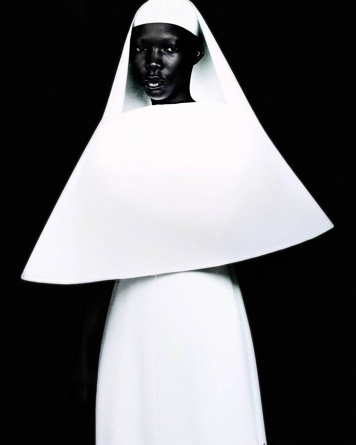 Figura humana con piel oscura vestida con un vestido blanco y un sombrero blanco en forma de campana, en un fondo negro.