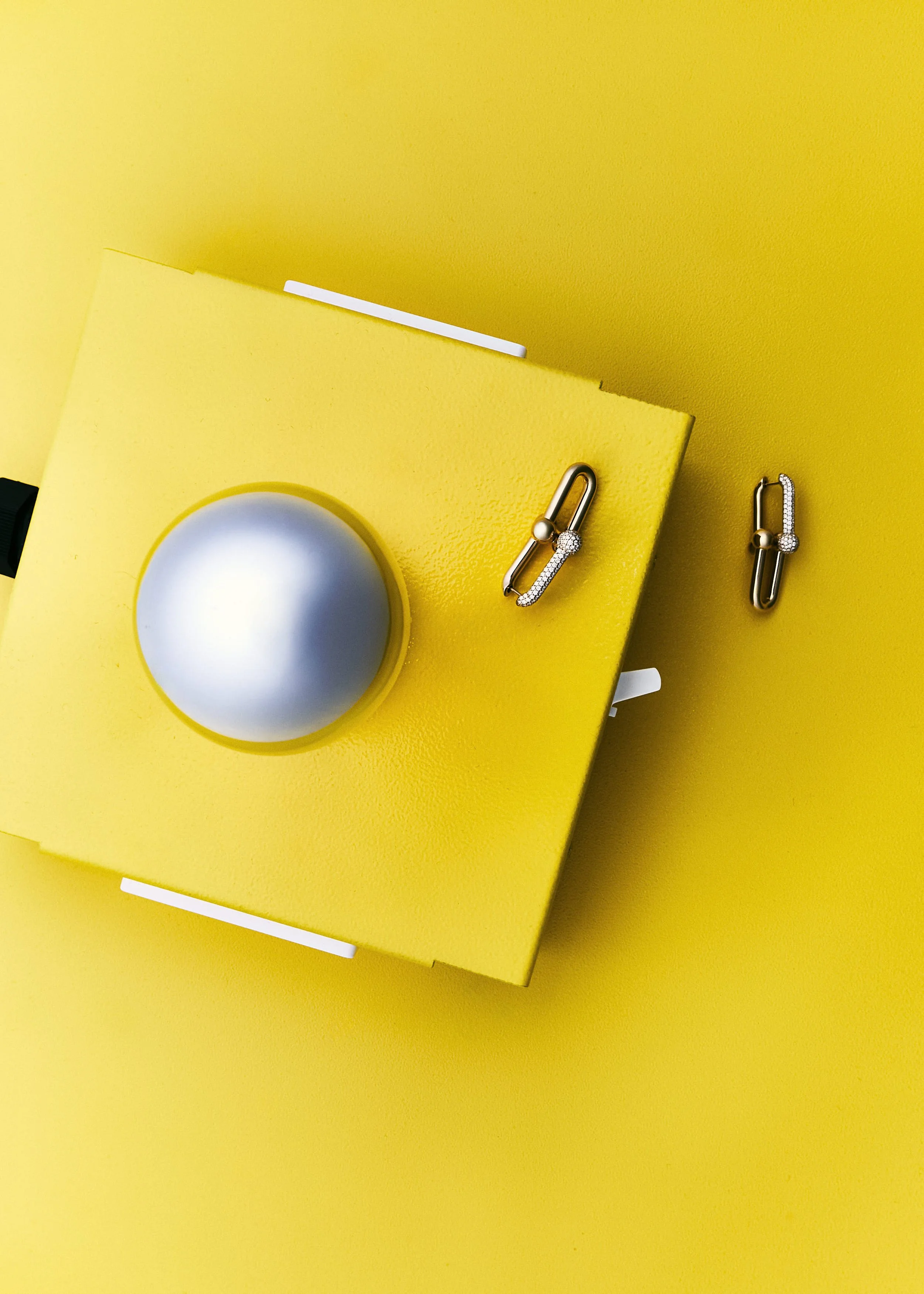Joyas de oro y diamantes, pendientes y broche, sobre fondo amarillo.