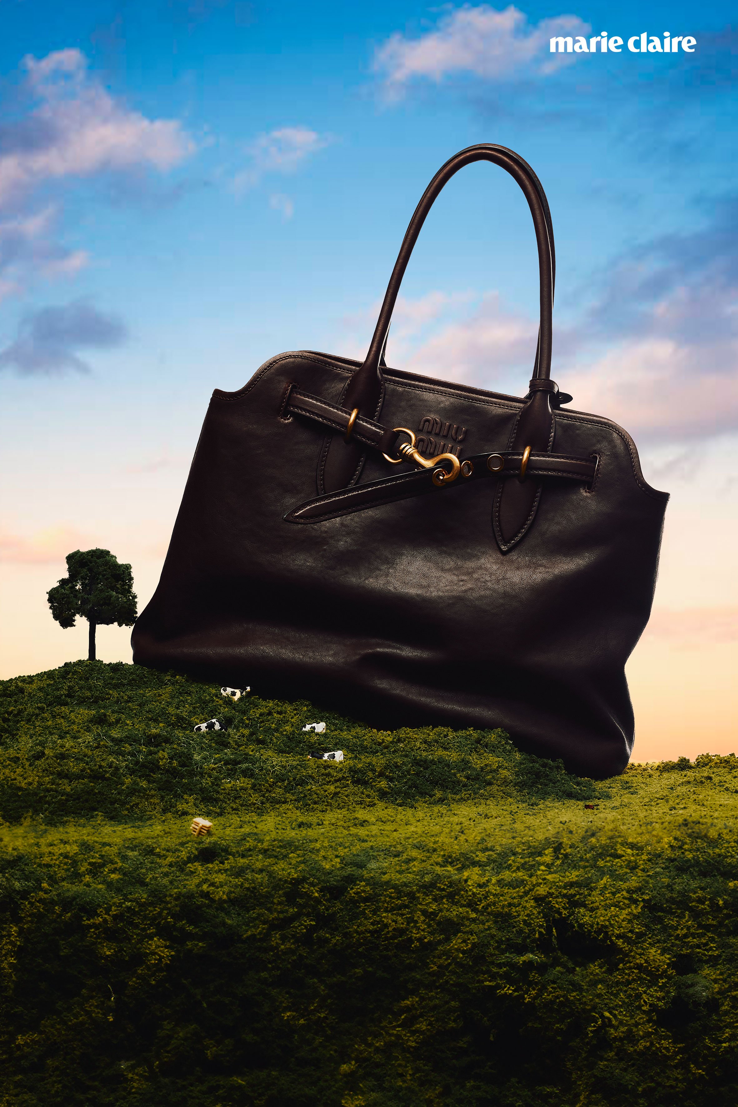 Bolso de piel negro flotando sobre un paisaje de colinas verdes con vacas, con cielo azul y nubes en el fondo.