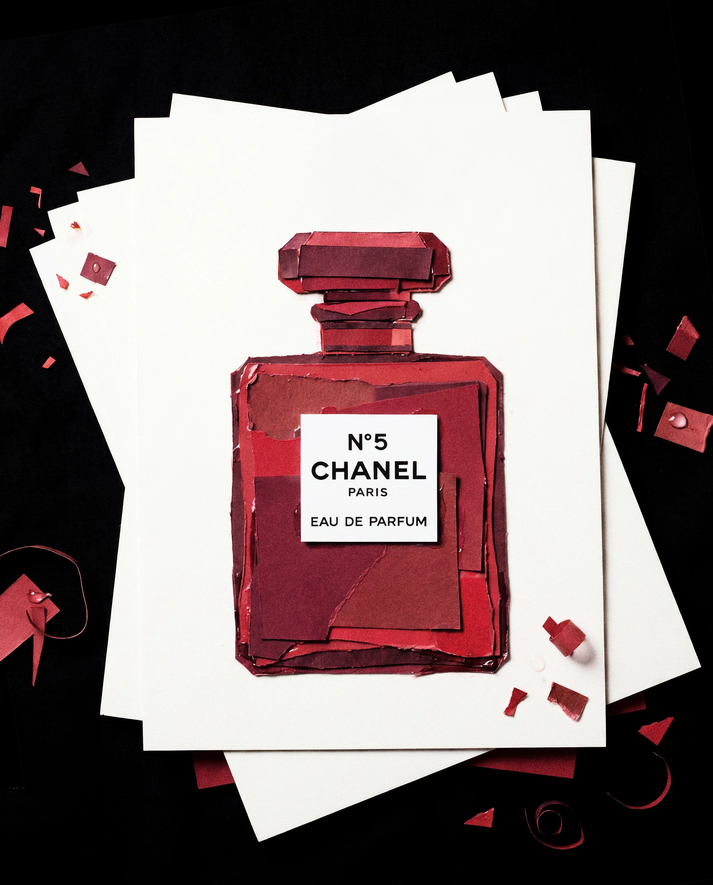 Cartel de perfume Chanel Nº 5 en un fondo negro, elaborado con recortes de papel con confeti rojo y blanco alrededor