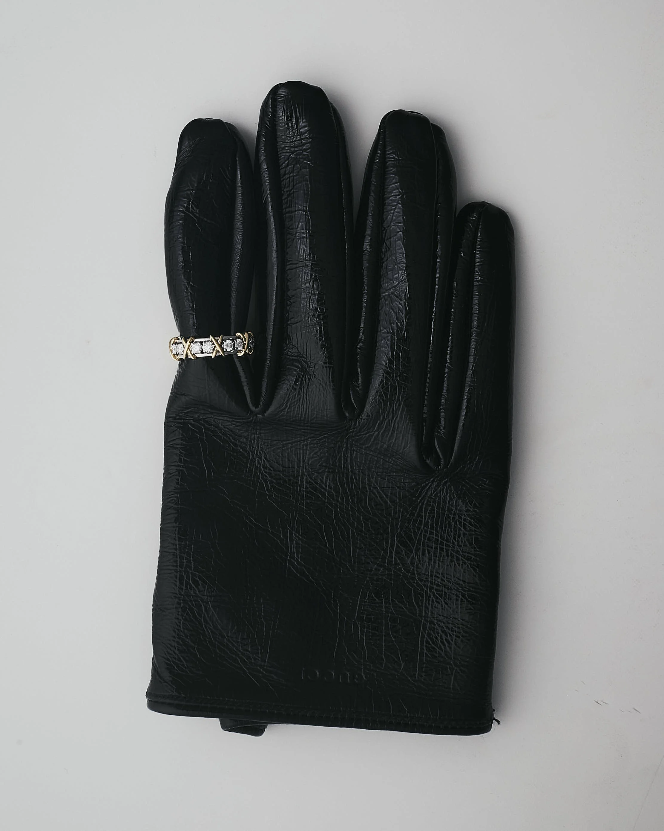 Tarjetero o billetera negra de material brillante, con un anillo decorativo con piedras