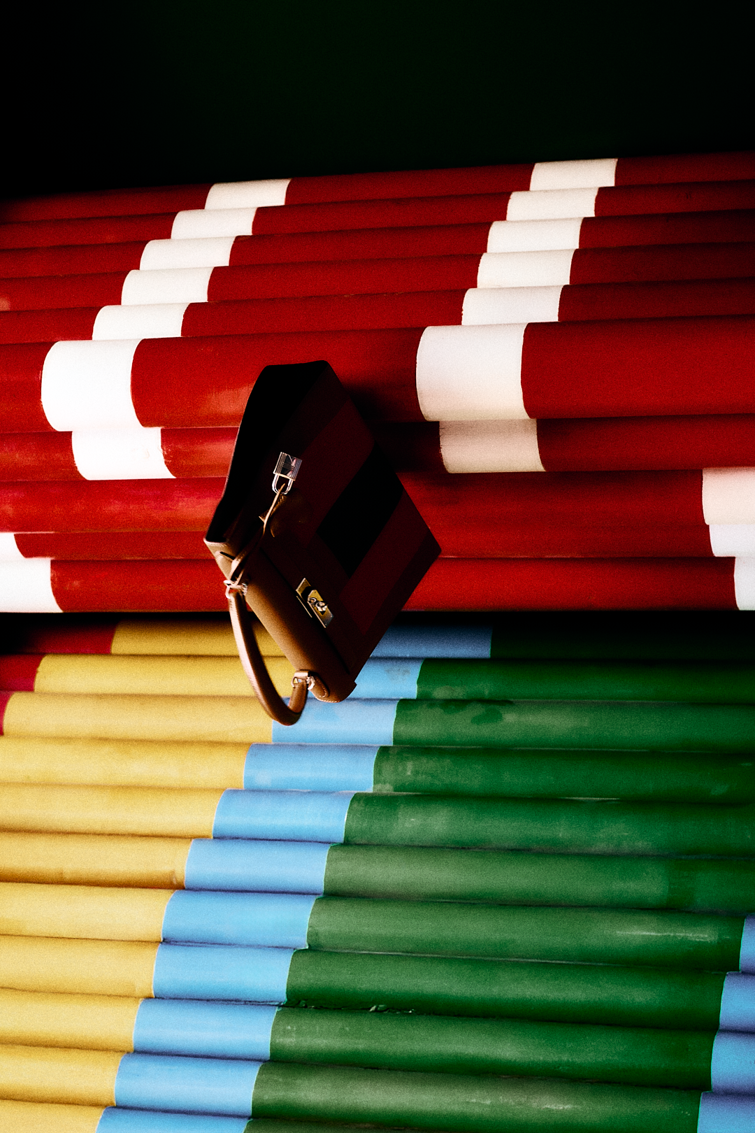 Piles de lápices de colores apilados, con un bolso negro colgado de uno de ellos.