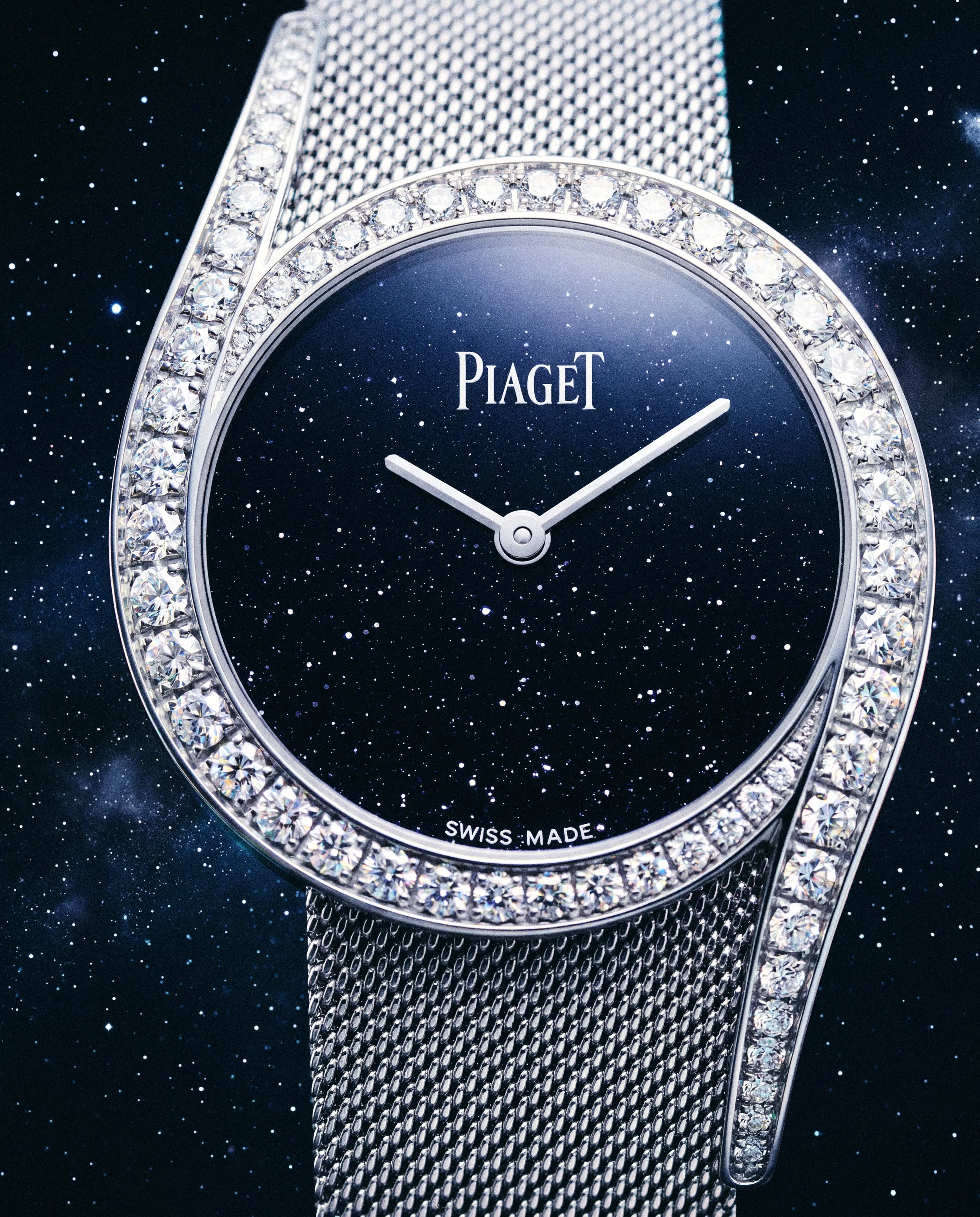 Reloj de lujo con esfera azul, bisel y pulsera decorados con diamantes y la marca Piaget visible en la esfera, sobre fondo de espacio estrellado.