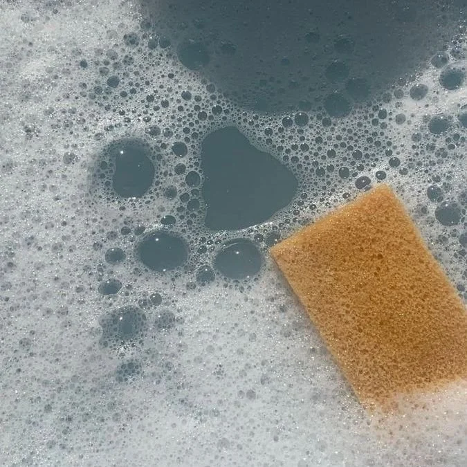 Cleaning sponge in soapy water with bubbles.