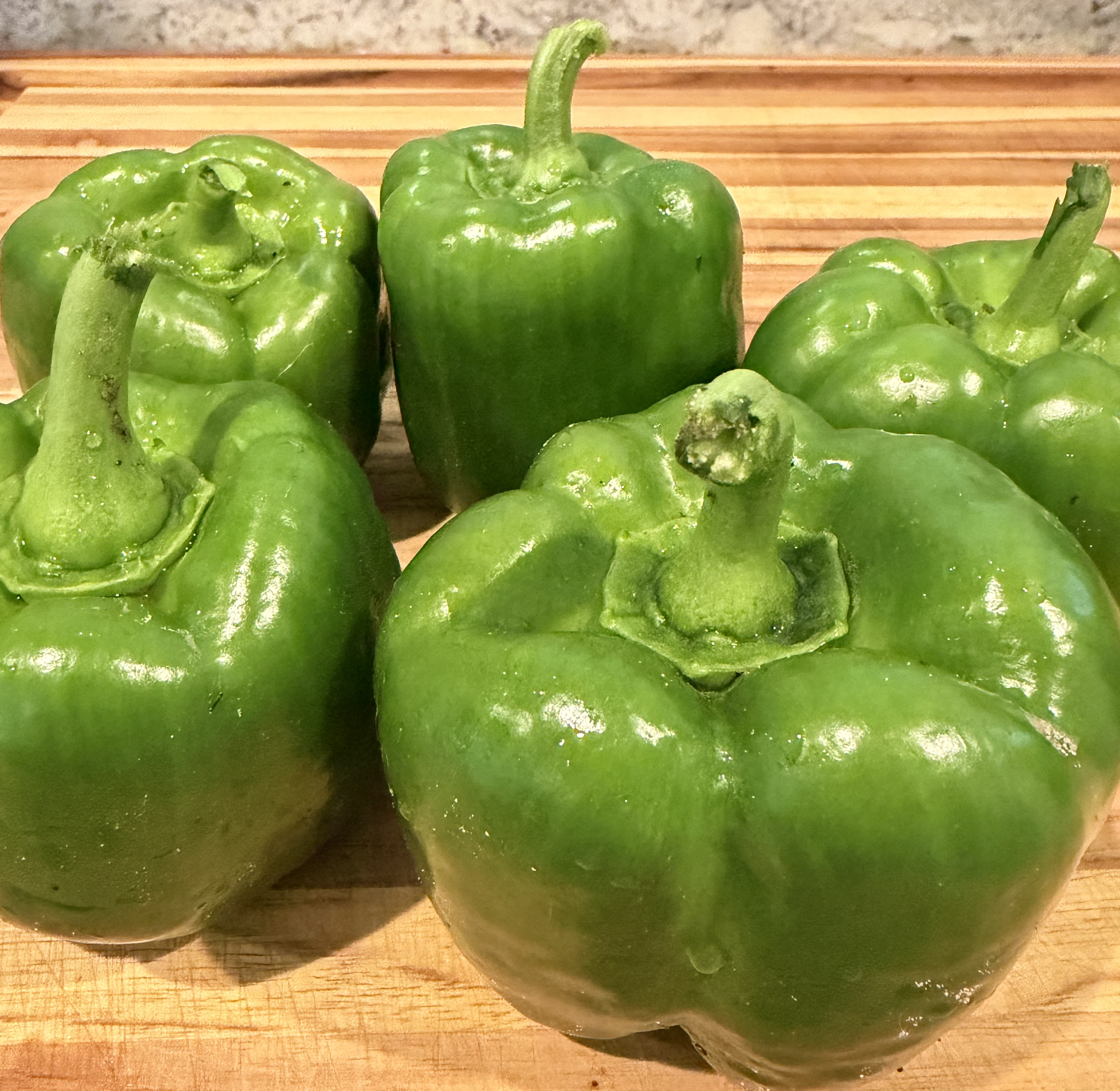 Green bell peppers on a wooden surface.