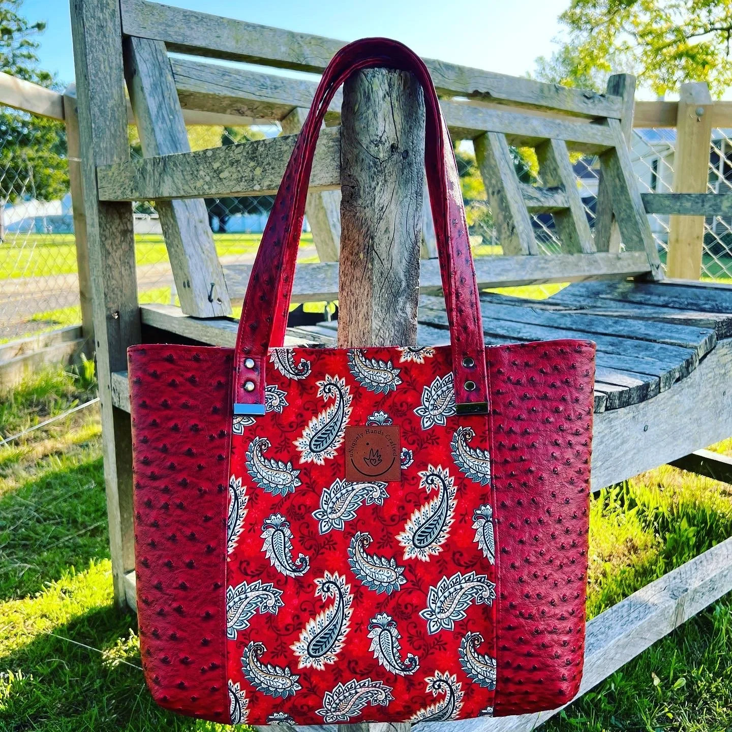 Custom handcrafted tote bag featuring red and grey paisley fabric with red faux ostrich leather, created as part of the uNiquely Hands Crafted Collection.