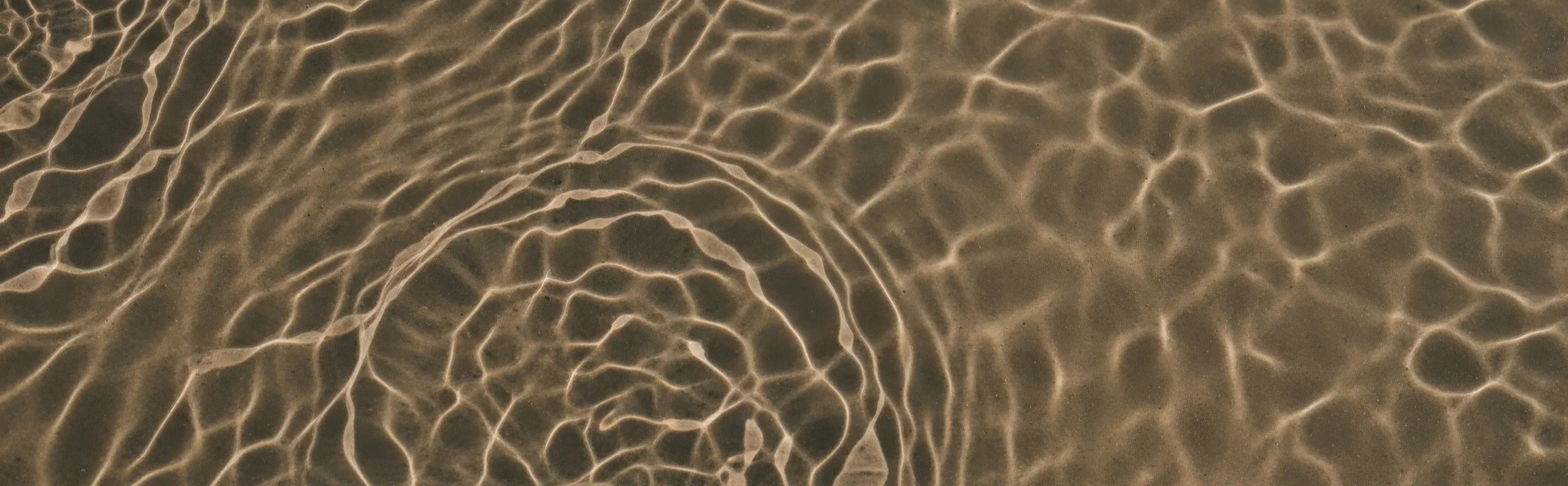 Close-up of water on the sand creating a pattern of light reflections.