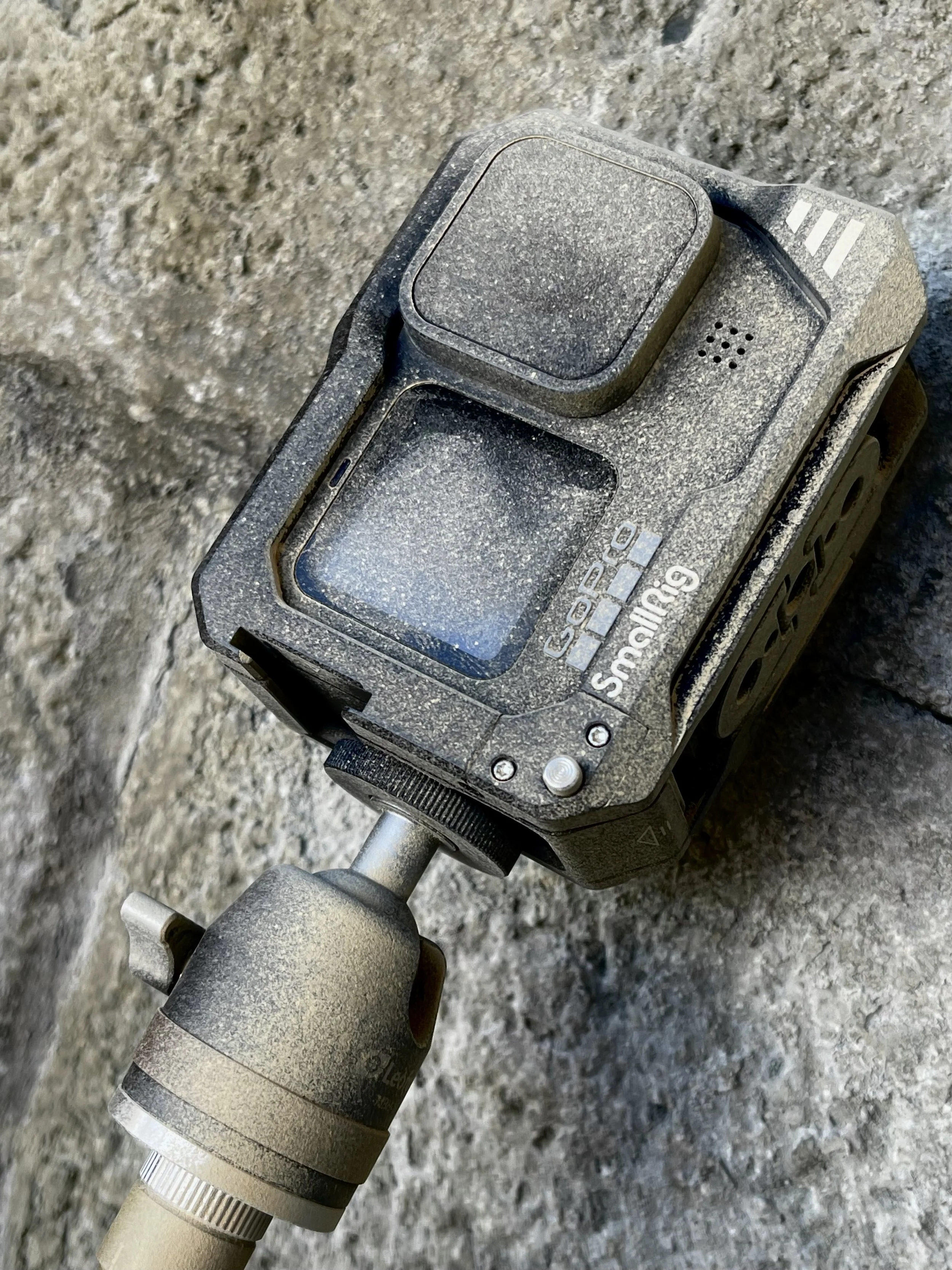 A close-up of a dust-covered drill with a yellowish handle, resting on a rough, gray, rocky surface.