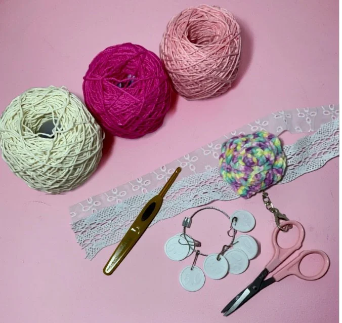 Matériel de création créative avec pelotes de laine colorées, chouchou en tissu et ciseaux de mercerie sur l'établi de Willou Créations.