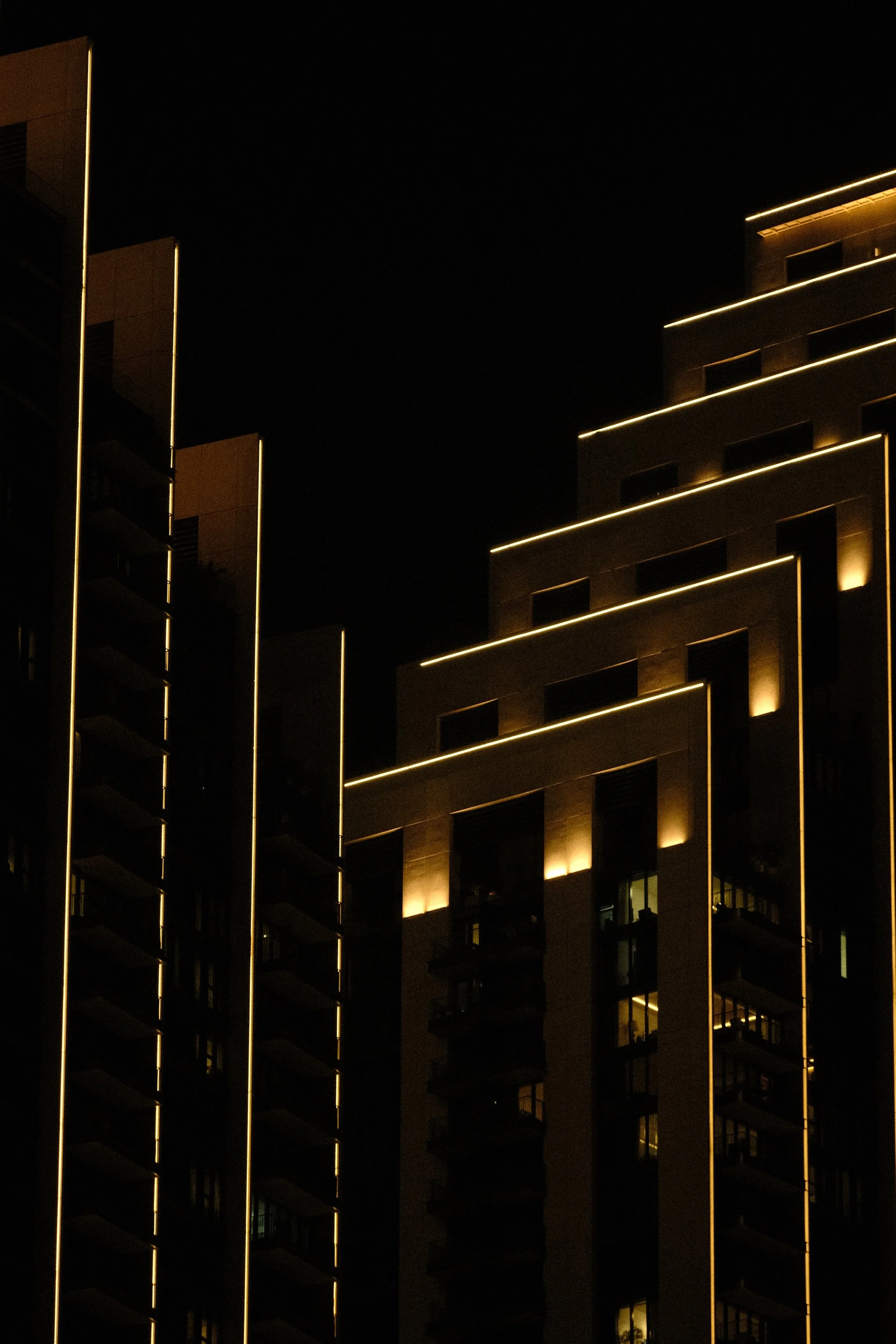 Nighttime view of a modern building with illuminated vertical and horizontal lines outlining its structure.