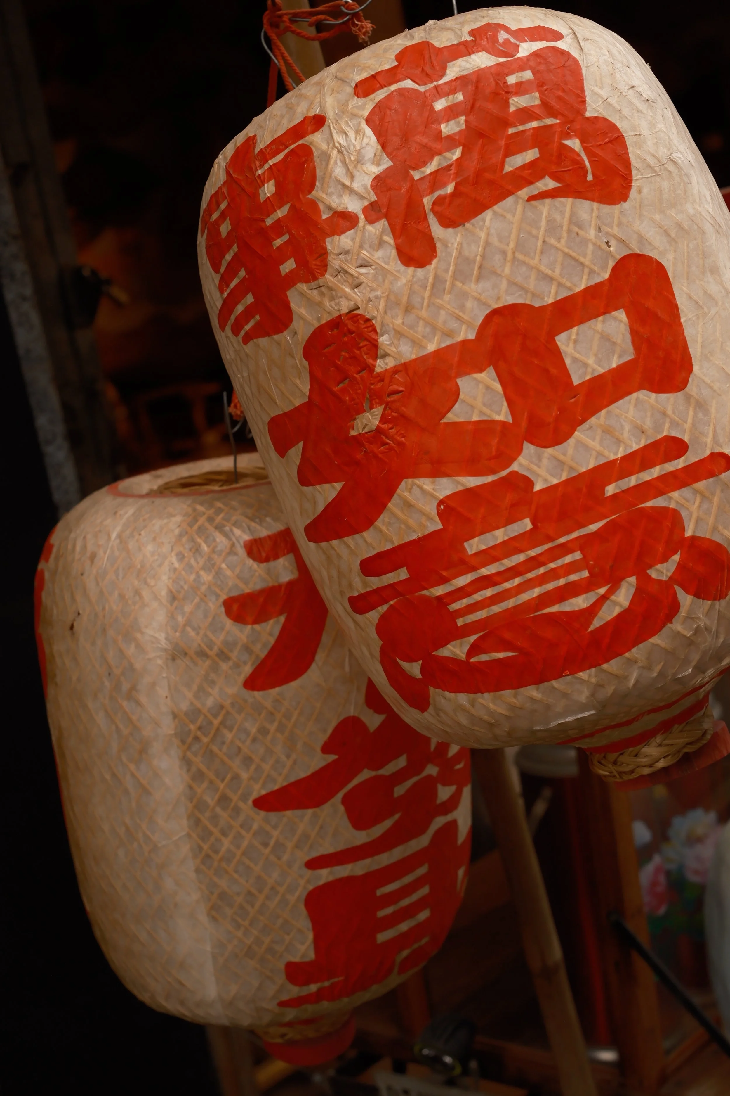 Close-up of traditional paper lanterns decorated with red Chinese characters, hanging in a row.