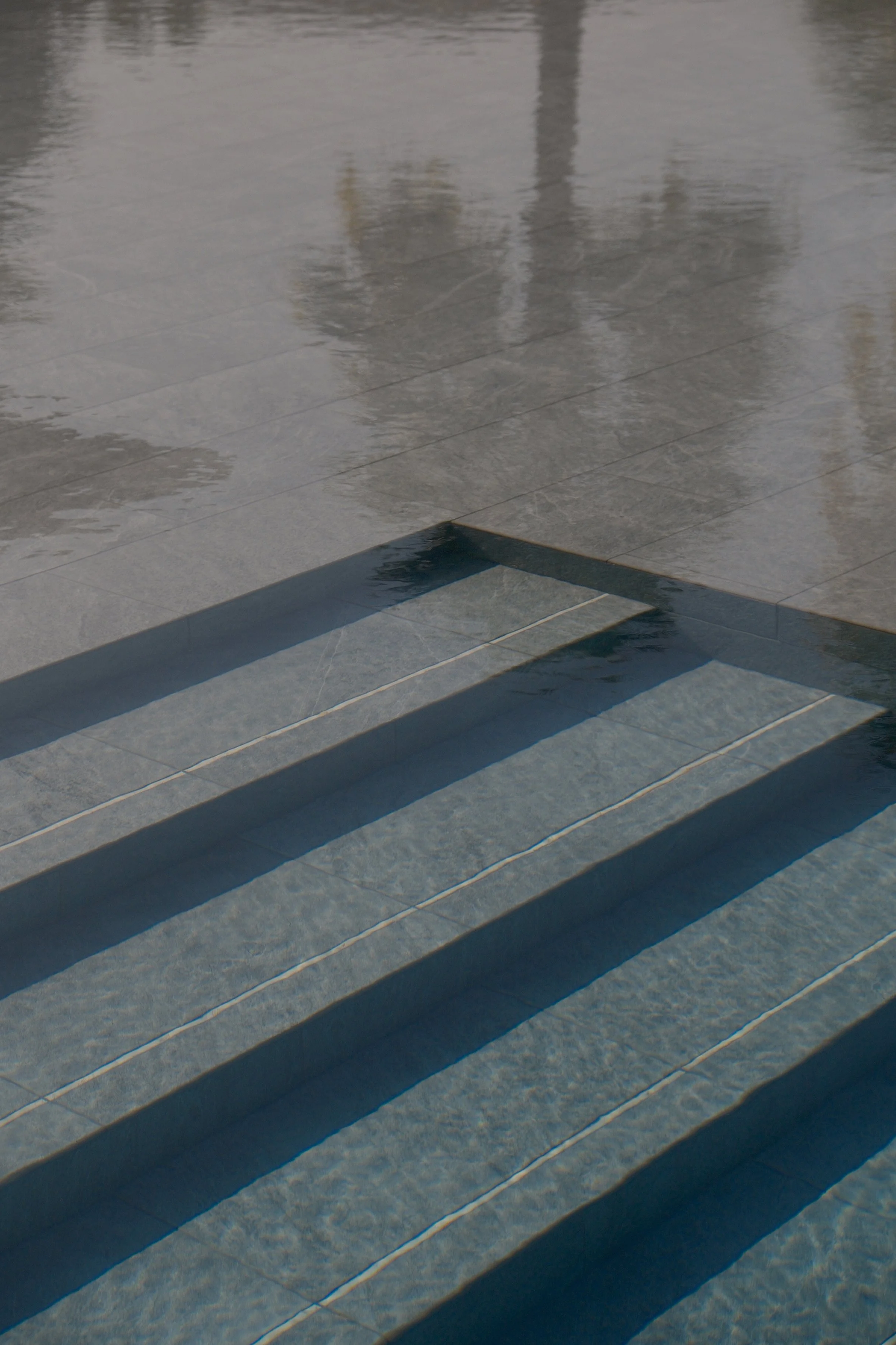 Wet tiled stairs with shadows cast across the surface.