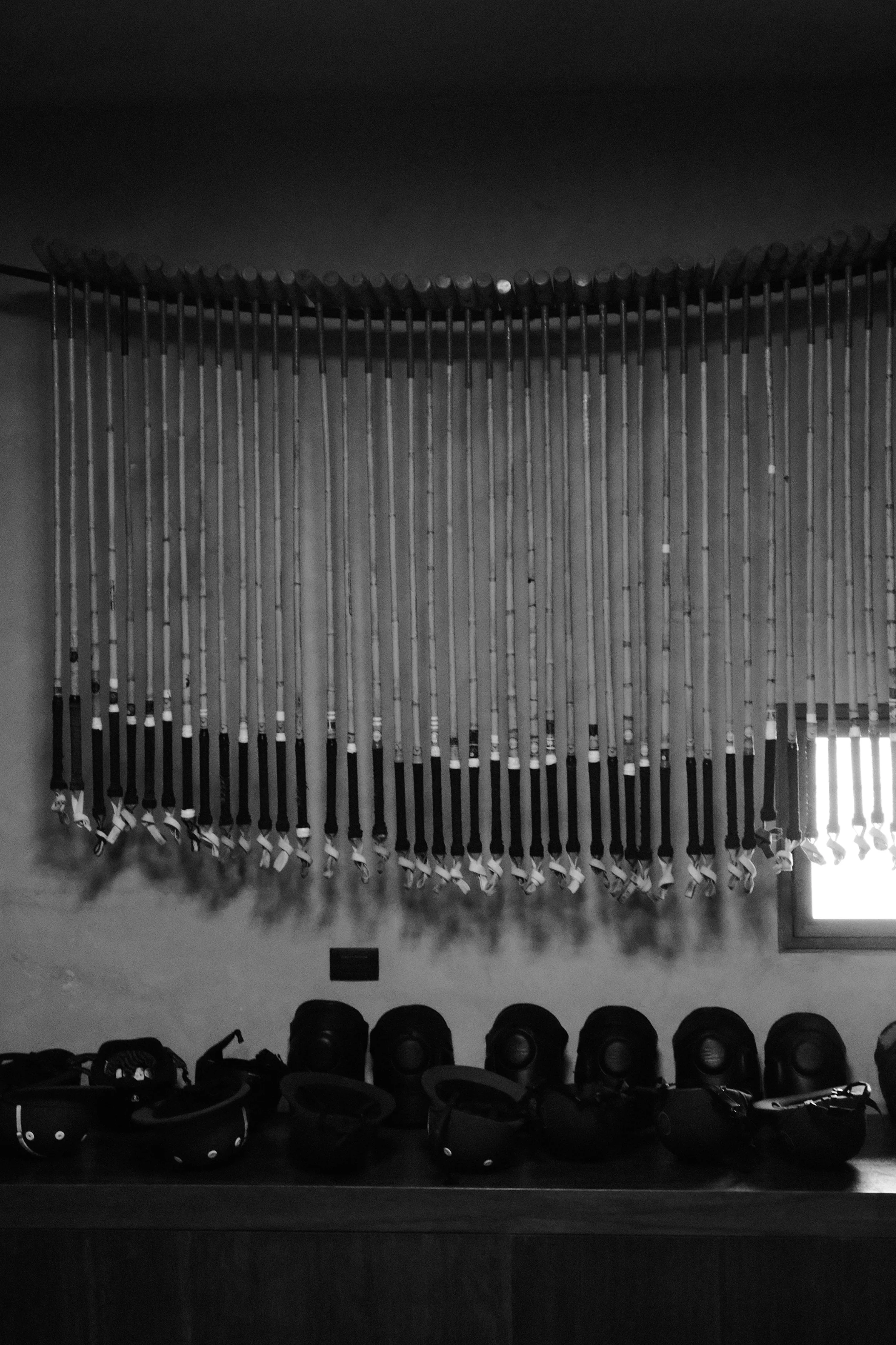 A room with a wall decorated with golf clubs hanging from a rail and golf shoes lined up on a shelf below.