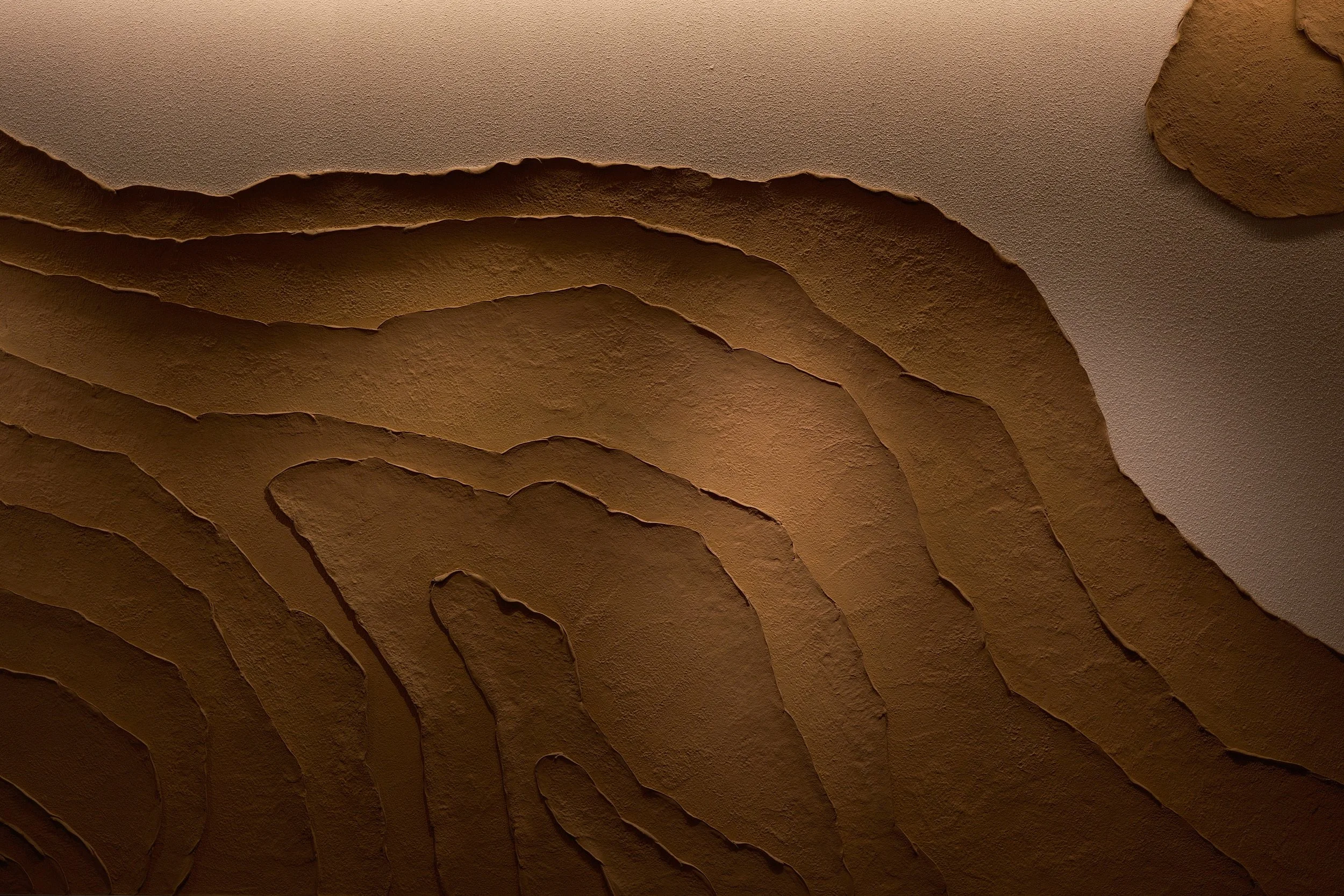 Close-up of a textured, layered, brownish-orange ceiling with a wavy, abstract pattern.