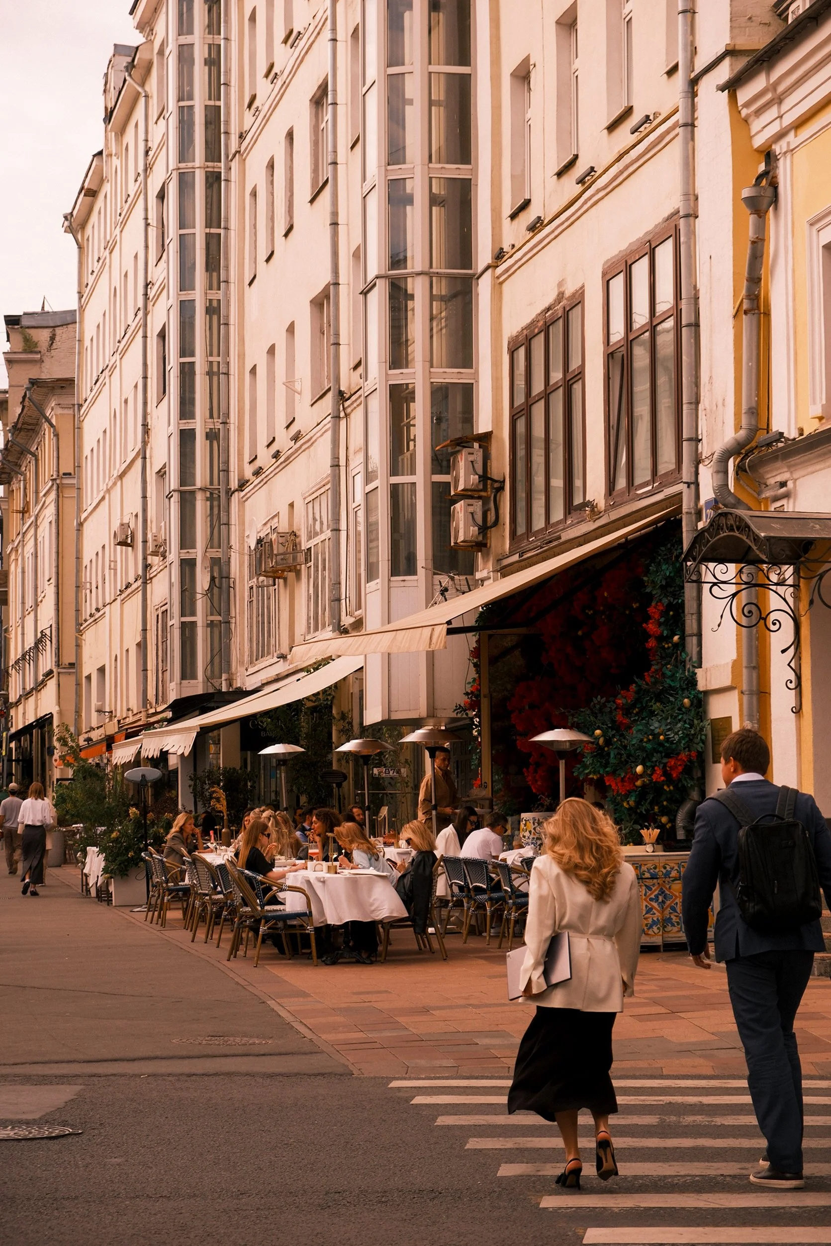 People dining at an outdoor restaurant on a city street, with buildings and windows above.