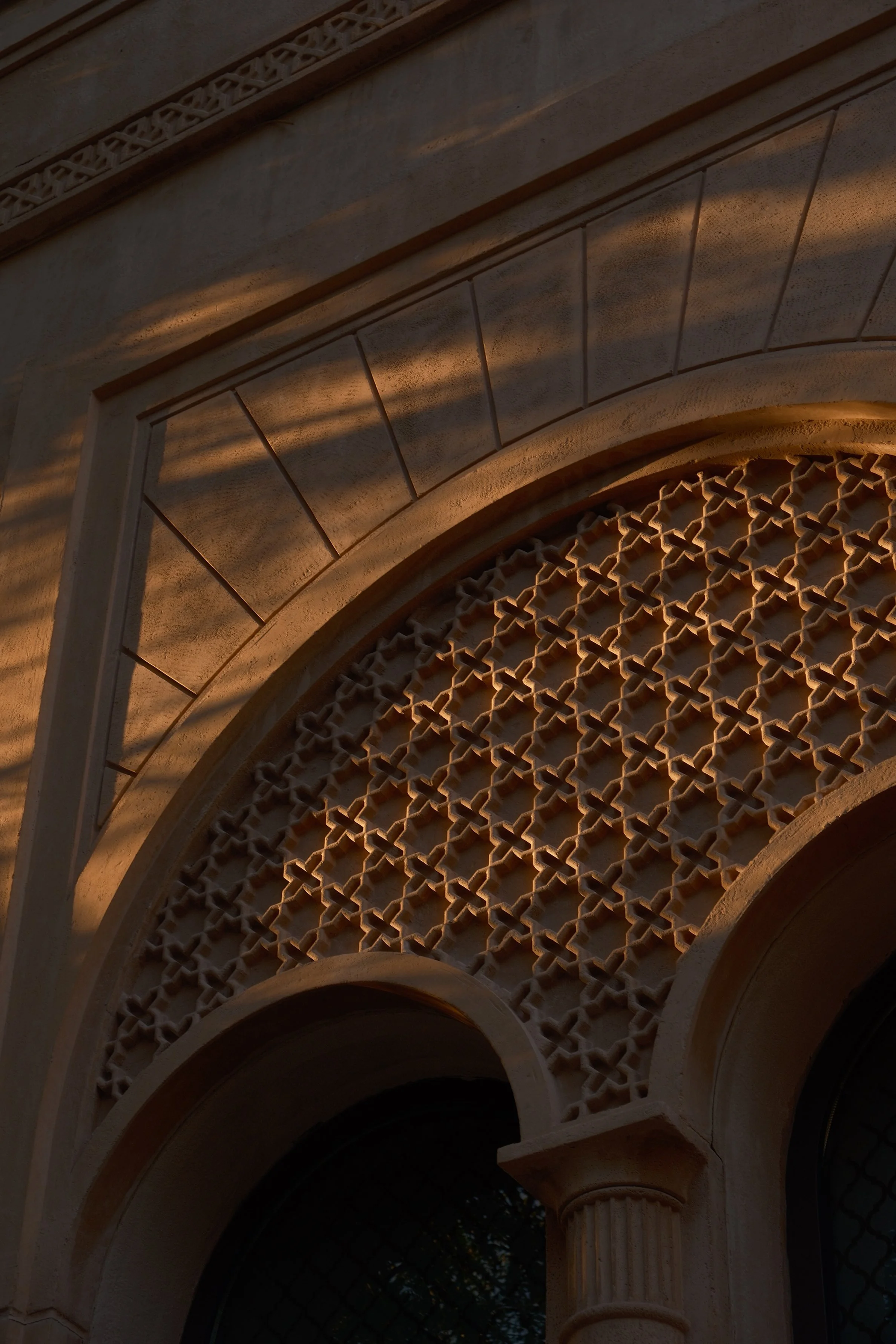 Close-up of an ornate architectural archway with intricate lattice and decorative stonework on a building.