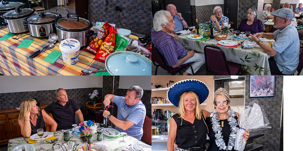 A collage of four photos from a social gathering. The first photo shows a table with slow cookers, snack bags, and snacks. The second photo features elderly people sitting at a decorated table, enjoying a meal. The third photo depicts three people at a dinner table, with one man pouring a drink into a glass. The fourth photo shows two women, one wearing a large blue hat and a lei, smiling in a kitchen setting.