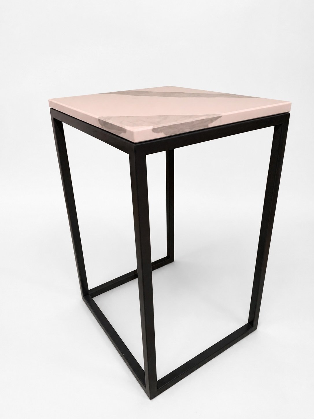 A modern side table with a pink marble top and black metal frame.