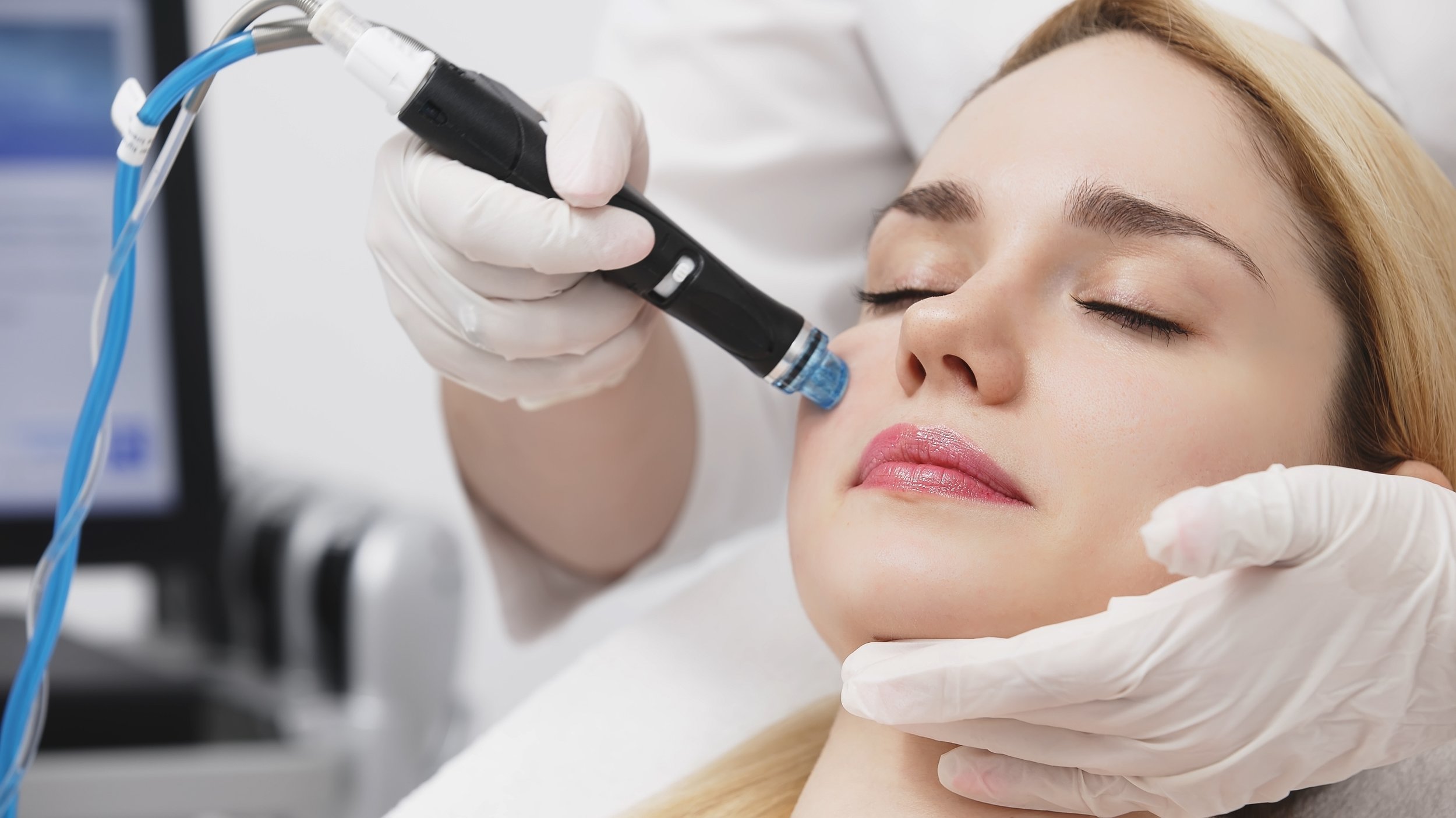 A woman receiving a cosmetic procedure on her lips from a professional in a clinical setting.