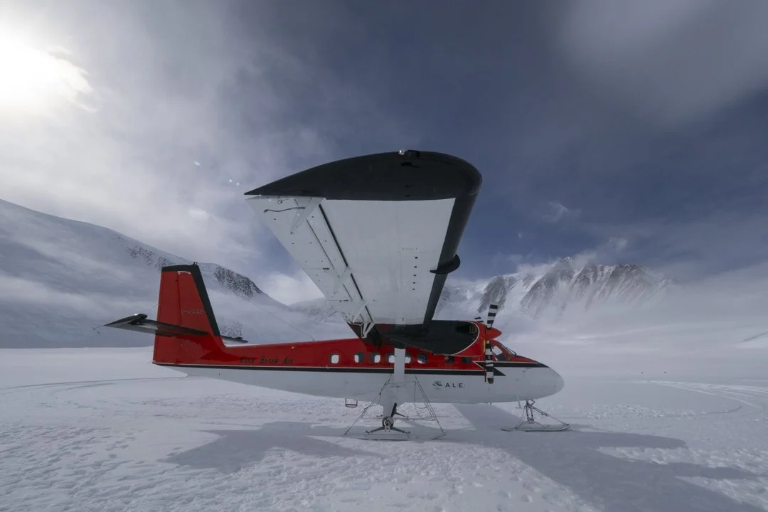 Twin Otter aircraft landing on the Antarctic ice during an emperor penguin photography expedition.