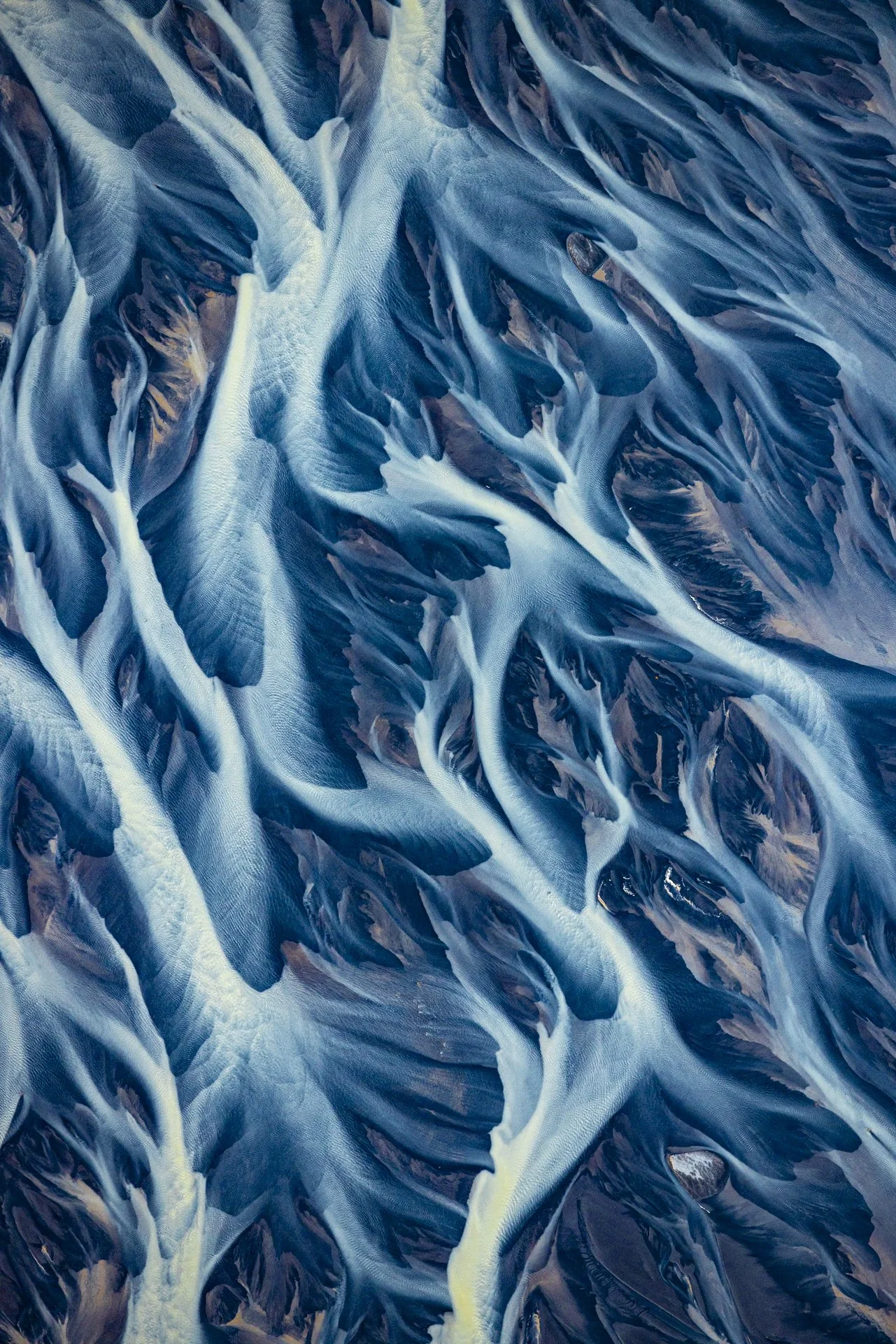 Abstract aerial view of braided glacial rivers flowing across Iceland's volcanic landscape.