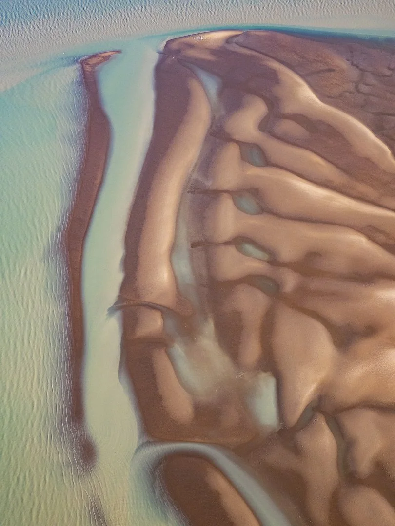 Aerial view of a rugged river delta with winding water channels and sandy banks.