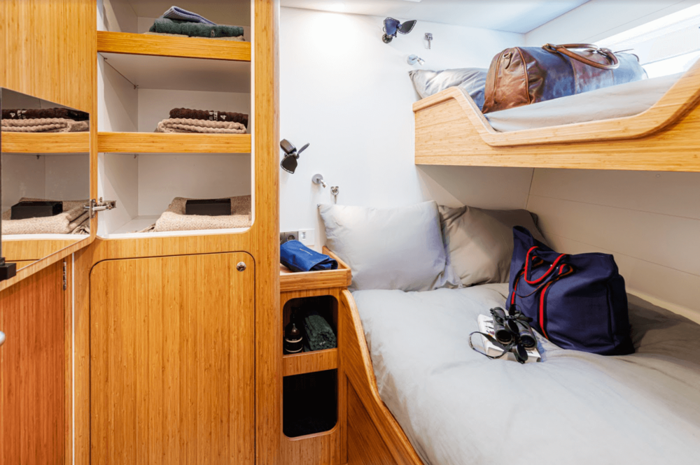 Bunk beds with travel bags, binoculars, and a small wooden cabinet in a cozy room.