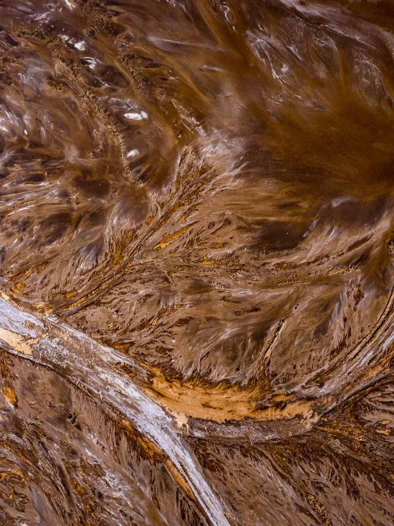 Close-up of a marble surface with swirling brown, tan, and white patterns.