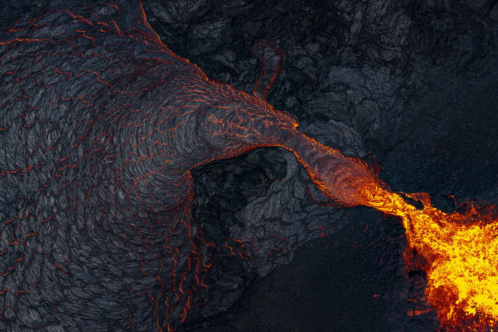 Molten lava flowing across a volcanic landscape during an eruption in Iceland.