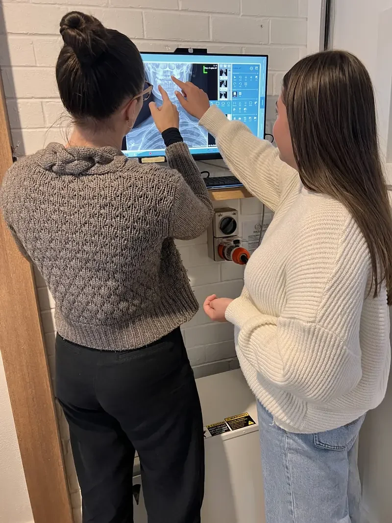 Dr Tia Deoki, a chiropractor reviewing X-ray images with a patient in a chiropractic consultation