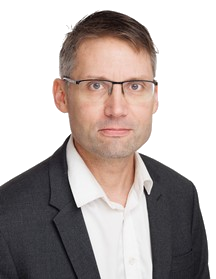 A man wearing glasses, a white shirt, and a dark blazer, with a serious expression on his face.