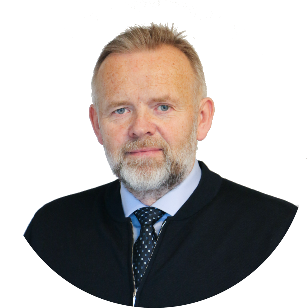 Portrait of an older man with light skin, gray beard, and blue eyes, wearing a black sweater, collared shirt, and patterned tie.