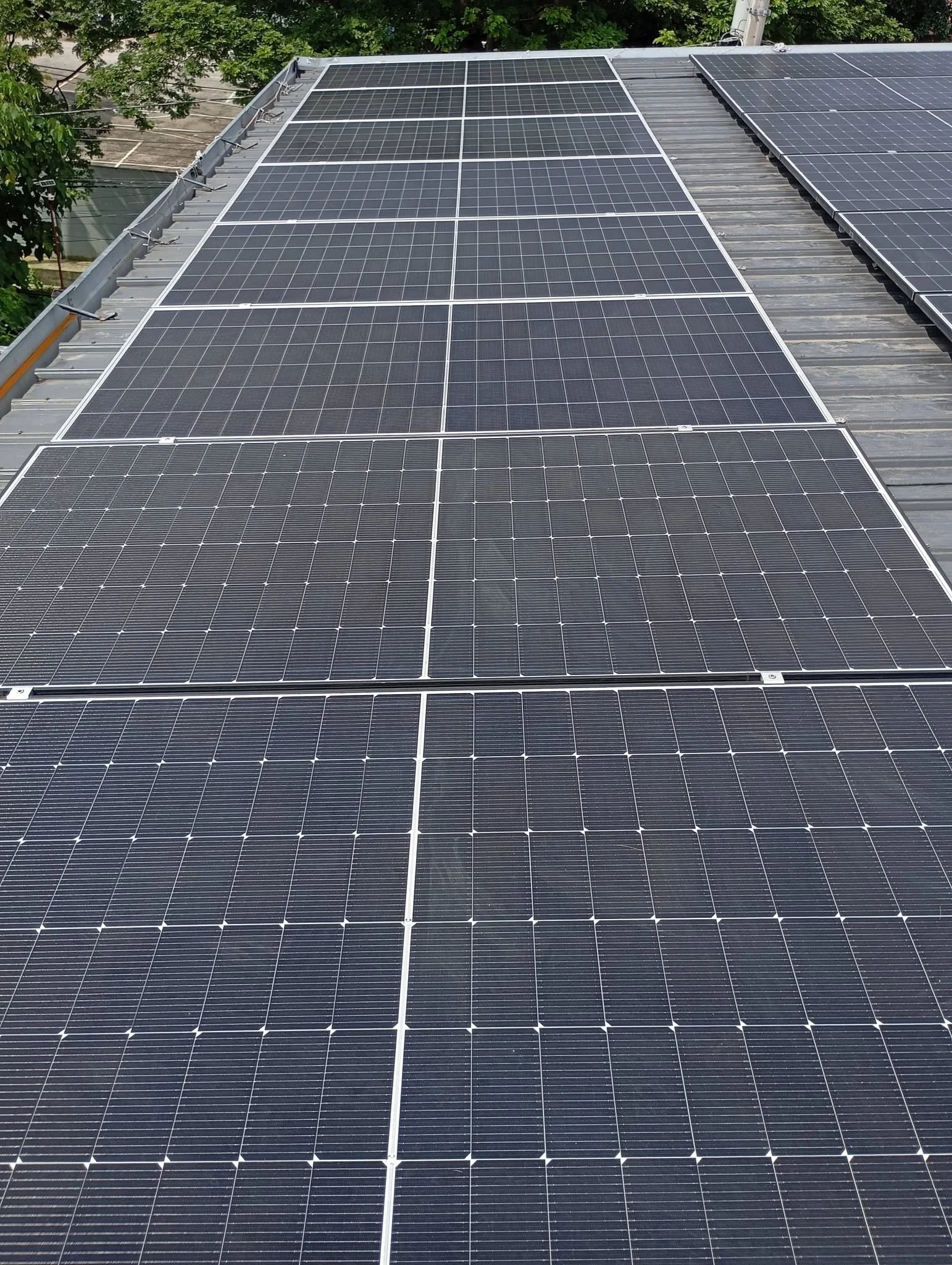 Multiple dark blue solar panels installed on a flat metal roof.