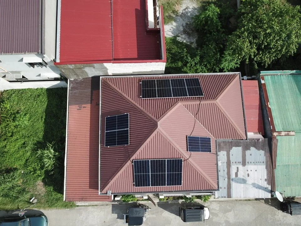 Aerial view of a house with a brown roof equipped with four solar panels.