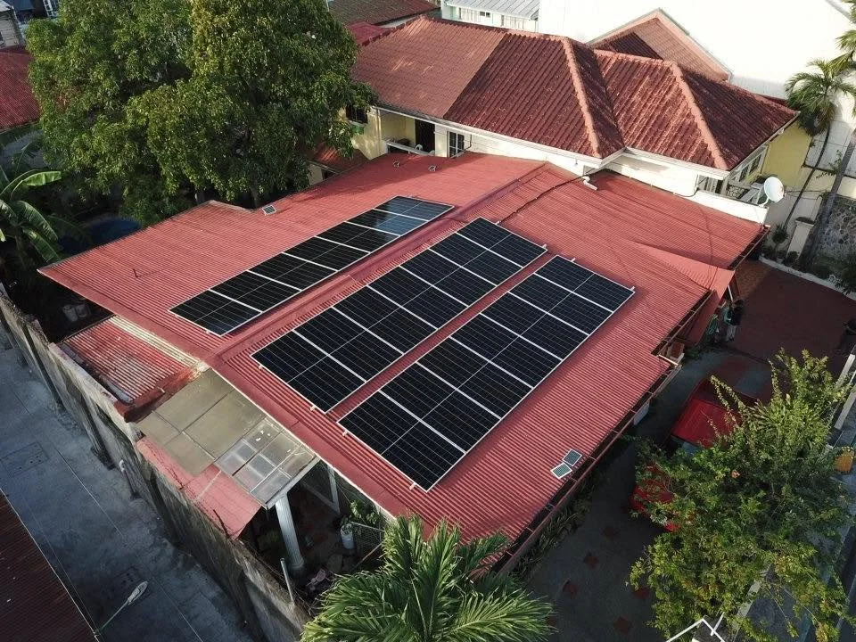 A red rooftop house with multiple solar panels installed on the roof.