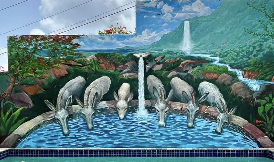 A mural of a scenic landscape with mountains, waterfalls, trees, and seven donkey heads painted around a water pool.